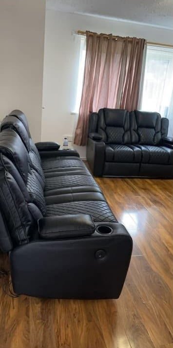 Black leather recliner sofas on a wooden floor